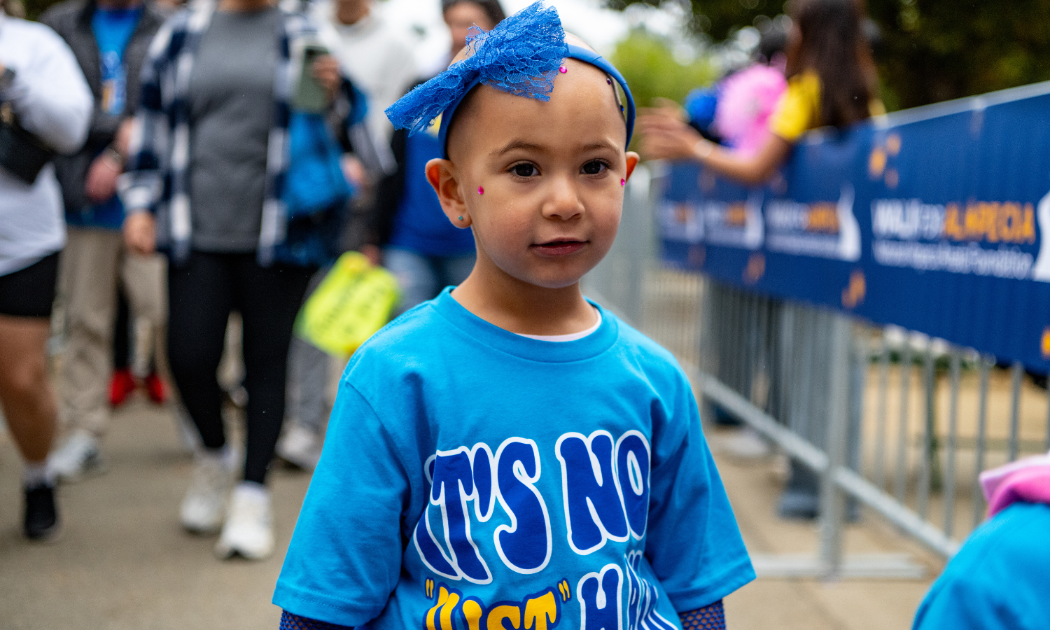 Young child in a Walk For Alopecia T-shirt, tutu, and headband